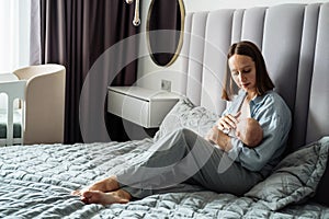 Home portrait of a newborn baby with mother on the bed.