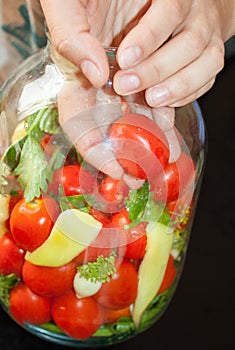 Home preserving of tomatoes. the hand settles the tomatoes in a jar for canning for the winter.