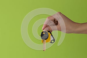 Home purchase concept. Keys with a keychain house in hand on a green background