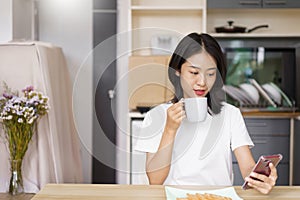 Home relaxation concept, Young woman drinking coffee and surf social media on smartphone at home