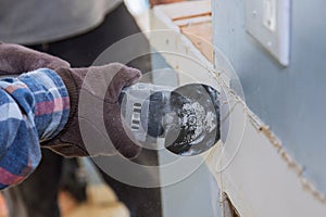 Home remodel of replacement damaged drywall on man is cutting gypsum board with utility hand electric power tools