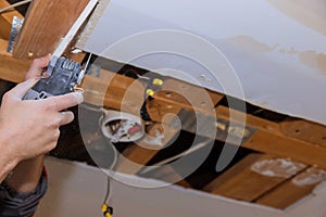 Home remodel of replacement damaged drywall on man is cutting gypsum board with utility hand electric power tools