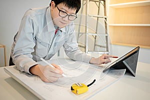 Asian male Interior worker working with architectural drawing