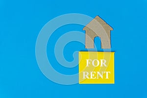 Home for rent. Property rent concept. Real estate sale sign under a small house made by paper cut on blue background