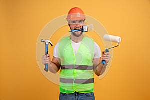 Home repair male worker busy with house renovation, holds building equipment, has sad expression, wears casual working clothes.