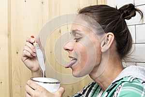 Home repair. Woman jokingly pretends that he wants to eat the white paint from the jar with a brush that holds, on the background