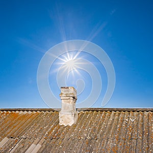 home roof with furnace pipe on the sunny sky background