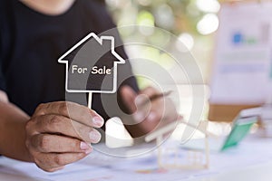 Home sale agent or house seller showing label house with text SALE. Mortgage concept. Real estate, moving home or renting property