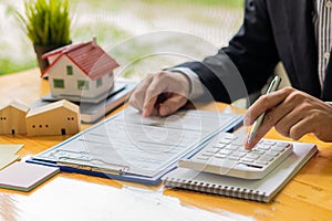 Home sales agents sit at the office and house designs with calculators and real estate agents and documents for home purchases, in