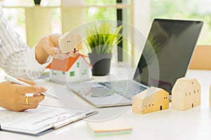 Home sales agents sit at the office and house designs with calculators and real estate agents and documents for home purchases, in