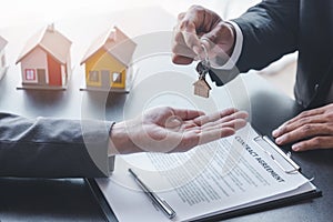Home sales,home rental and real estate concept.Hands of estate agent giving keys to the Customer after sign the document while
