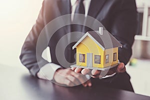 Home sales,home rental and real estate concept.Hands of estate agent holding house model present to the Customer while explain