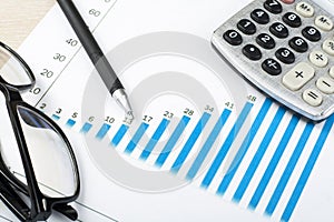 Home savings, budget concept. Chart, pen, calculator and glasses on wooden office table