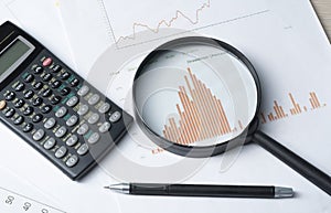 Home savings, budget concept. Chart , pen, calculator and magnifying glass on wooden office table.