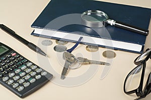 Home savings, budget concept. Model house, notepad, pen, calculator and coins on wooden office desk table.