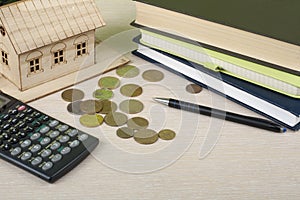Home savings, budget concept. Model house, notepad,, calculator,pen and coins on wooden office desk table.