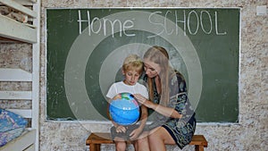Home school concept. A mother gives her children a geography lesson with a globe in her hands.
