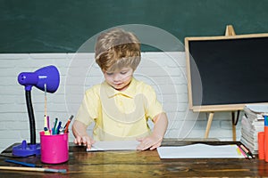 Home or school education. Portrait child from elementary school. Funny little kid pointing up on blackboard. Concept of