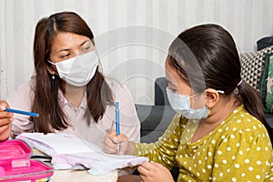 Home schooling concept image with mother and daughter studying while wearing face masks because of current corona virus threat photo