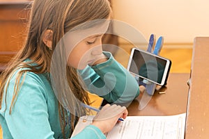 Home schooling. schoolgirl studying homework math during her online lesson at home, social distance during quarantine photo