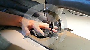 Home seamstress sews. Female hands sew jeans. A sewing machine works.