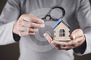 Home search concept. Holds a magnifying glass and a house