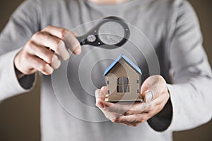 Home search concept. Holds a magnifying glass and a house