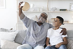 Home Selfie. Smiling black grandfather with preteen grandson taking photo together