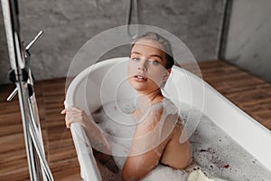 Home spa. Portrait of pretty lady resting in bubble bathtub, beautiful woman relaxing in modern bathroom interior