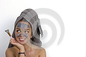 Home Spa Woman applying Facial clay Mask. Beauty Treatments. Close-up portrait of beautiful girl with a towel on her head applying
