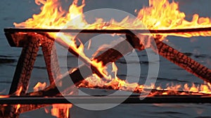Home style video. No sound. Slats falling down thirty 30 seconds. Extreme close-up video of a burning picnic table.