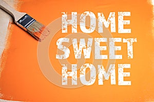 HOME SWEET HOME. Paint brush and orange on a wooden background