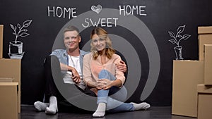 Home sweet home phrase on wall, happy family smiling at camera, mortgage