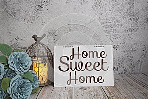 Home Sweet Home text message with flower and LED candle light on wooden background