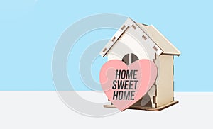Home sweet home word in wooden heart model and wooden house on blue background