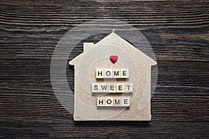 Home symbol with quote and heart shape on wooden background.