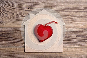Home symbol with red heart on wooden background.