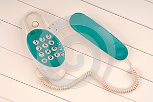 Home telephone is on white background, green phone device is on photo