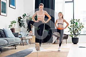 Home training. Mother and daughter warming up, stretching leg muscles