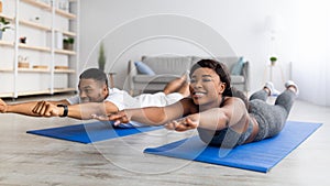 Home trainings during covid lockdown. Strong black couple exercising on sports mats, doing yoga or pilates indoors