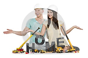 Home under construction: Happy couple with machines building home-word.