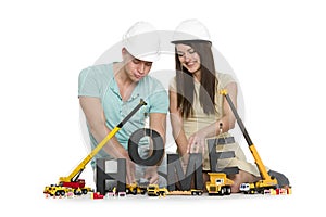 Home under construction: Joyful couple with machines building ho