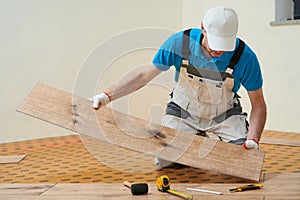 vinyl floor installation. Close-up hands of worker at home flooring renovation. photo