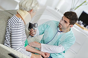 Home visiting nurse taking elderly womans blood pressure