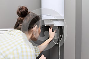 Home water heater, woman regulates the temperature on an electric water heater photo