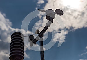 Home weather station on a background of blue sky with the sun behind the clouds. Measurement of temperature, humidity and wind dir