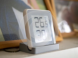 Home weather station standing on a shelf in the room. A modern device with a screen showing the temperature and humidity in the