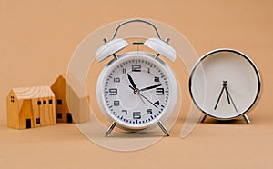 home white alarm clock with small model wooden house home loan finance and time