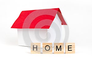 Home- word composed fromwooden blocks letters on red background, layout of a house with a red roof. copy space for ad photo