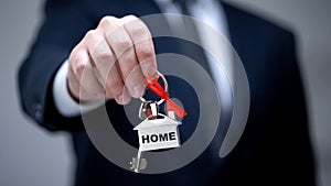 Home word on keychain in businessman hand, house purchase, rental services